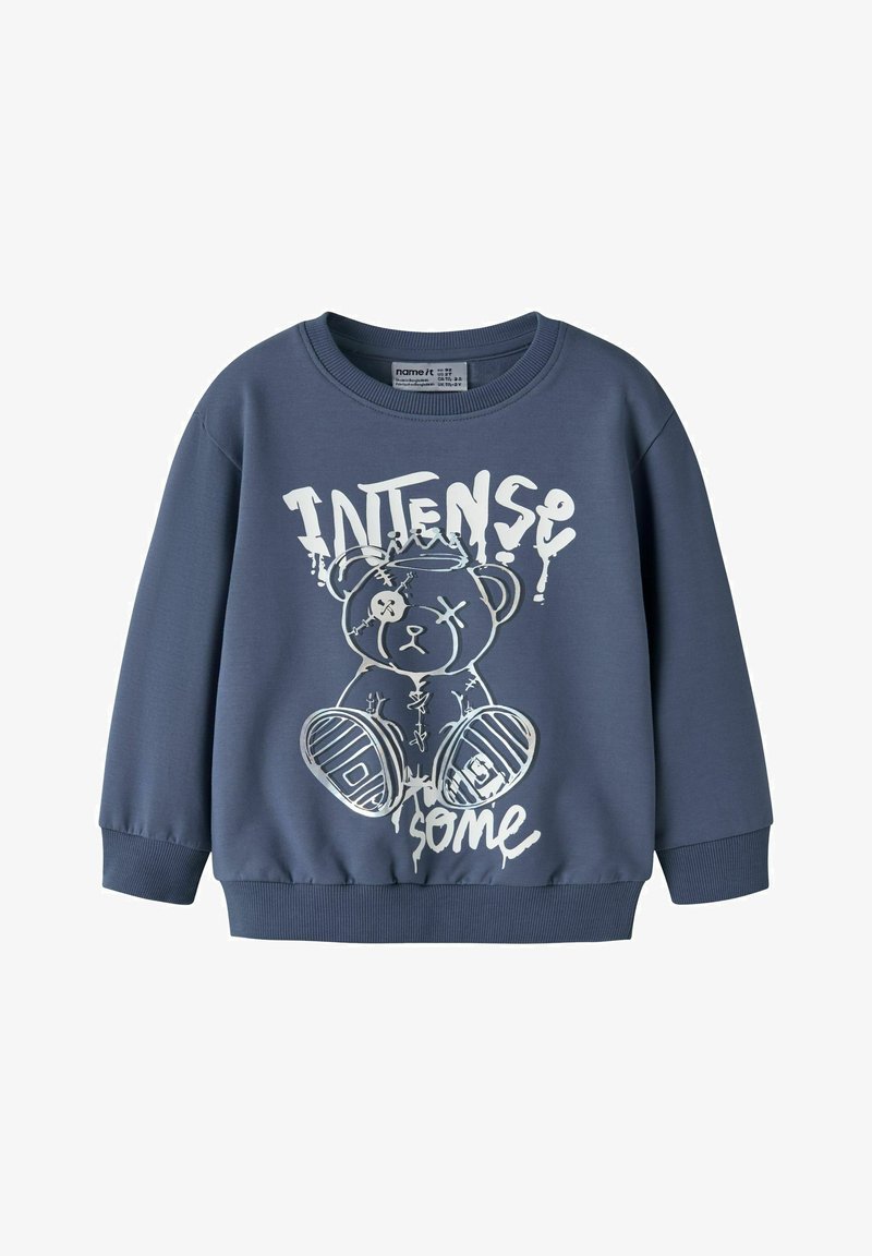 Blauwe sweatshirt met lange mouwen met een afbeelding van een gestikte teddybeer met een ooglapje en de tekst "INTENSE some" in wit.