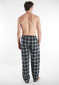 Geruite loungebroeken in marineblauw en groen, met een elastische tailleband en een comfortabele pasvorm. De stof lijkt zacht met een subtiele textuur.