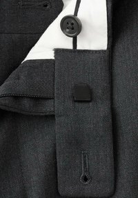 Ciemnoszary materiał o gładkiej teksturze, z czarnym guzikiem, białą podszewką i detalem w postaci patki do zapinania. Widoczny jest zamek błyskawiczny na krawędzi.