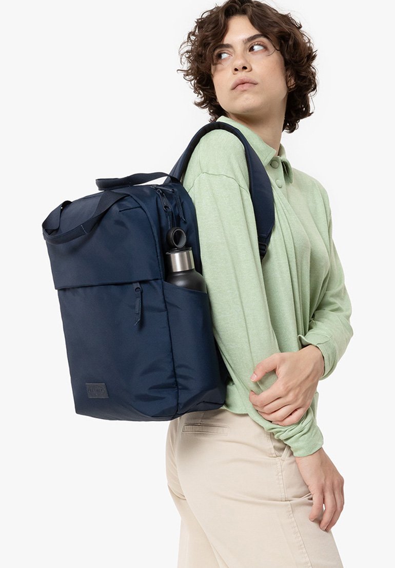 Navyblauer Rucksack mit Reißverschluss und einer Seitentasche für eine Wasserflasche, aus strapazierfähigem Material, einseitig getragen.