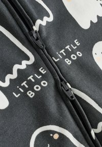 Vetoketjullinen haalari pehmeästä tummanharmaasta kankaasta. Sisältää valkoisia haamukuviota ja tekstiä "LITTLE BOO" erottuvilla väreillä.