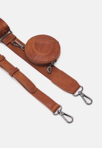 Brun læderjusterbar rem med en rund lynlåspose. Har metalclips, en glat tekstur og ensartet syning.