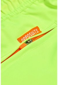 Neon žalios spalvos audinys su lygia tekstūra, turintis oranžinį užtrauktuką ir oranžinį logotipą su užrašu "OPPOSUITS."