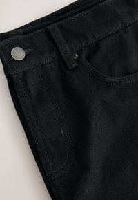 Sorte denimjeans med et klassisk design med fem lommer, lukning med metal-knap og tydelige syninger langs sømmene.