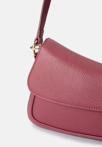 Textured burgundy shoulder bag with a flap closure, featuring a gold-toned hardware accent and a slim leather strap.