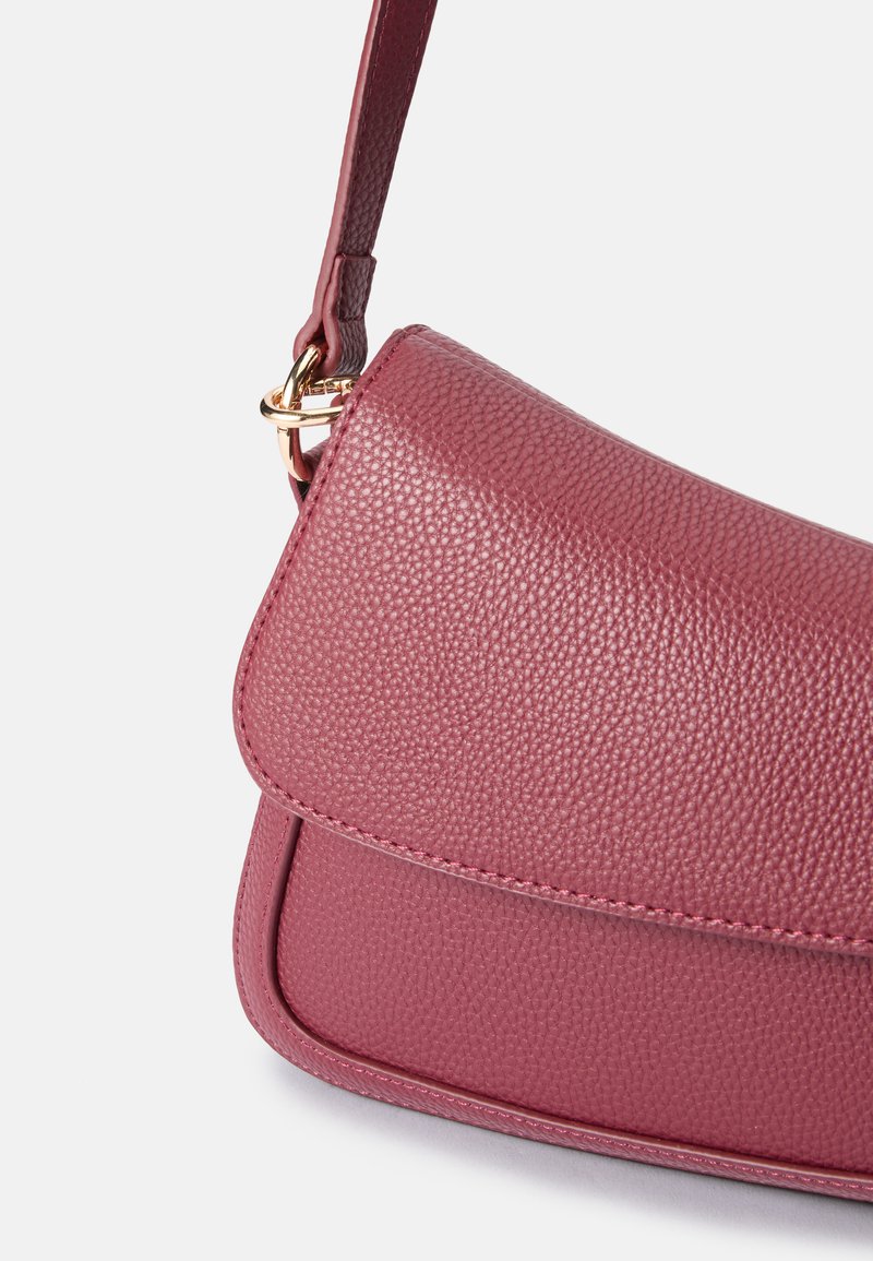 Bolso de hombro burdeos texturizado con cierre de solapa, que presenta un acento en hardware dorado y una correa de cuero delgada.