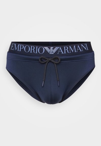 Bañadores azules con cordón y una cintura elástica que presentan el logo "Emporio Armani" en letras claras. Textura de tela suave.