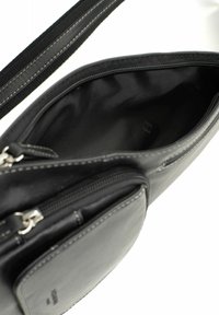 Borsa in pelle nera con compartimento principale con zip, dotata di una tasca frontale più piccola, design sottile e dettagli di cucitura a contrasto.