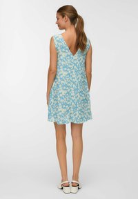 Blaues Blumenkleid mit V-Ausschnitt, locker sitzend und aus leichtem Stoff. Das Muster besteht aus hellen und dunklen Blautönen.