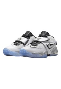 White sneakers with black accents, silver details, and a transparent blue sole. Features a strap with branding and textured surface elements.