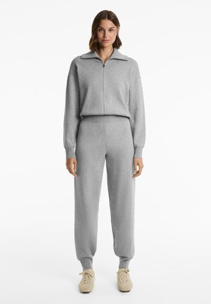 Set gri format din două piese, format dintr-un top cu fermoar și guler, cu manșete ribbate, și o pereche de pantaloni jogger asortați, cu talie elasticizată.