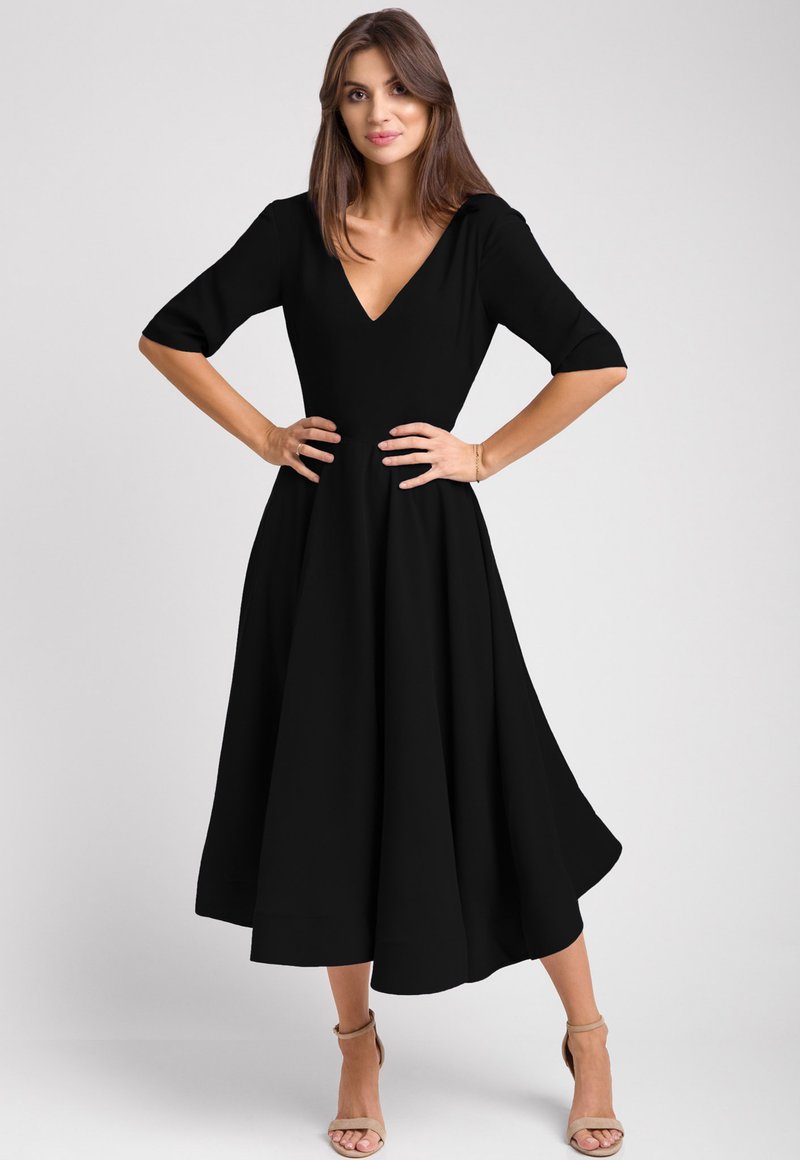 Czarna midi sukienka z dekoltem w kształcie litery V, rękawami o długości trzech ćwierci oraz rozkloszowanym dołem. Wykonana z gładkiego materiału, cechuje się dopasowaną talią i delikatnym drapowaniem.