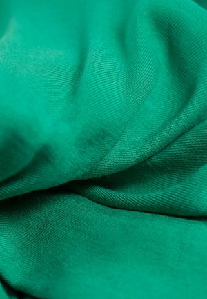 Grüner Stoff mit einer glatten Textur und feinem, schrägem Gewebe. Das Material ist gerafft und zeigt seinen weichen Fall und die lebendige Farbe.