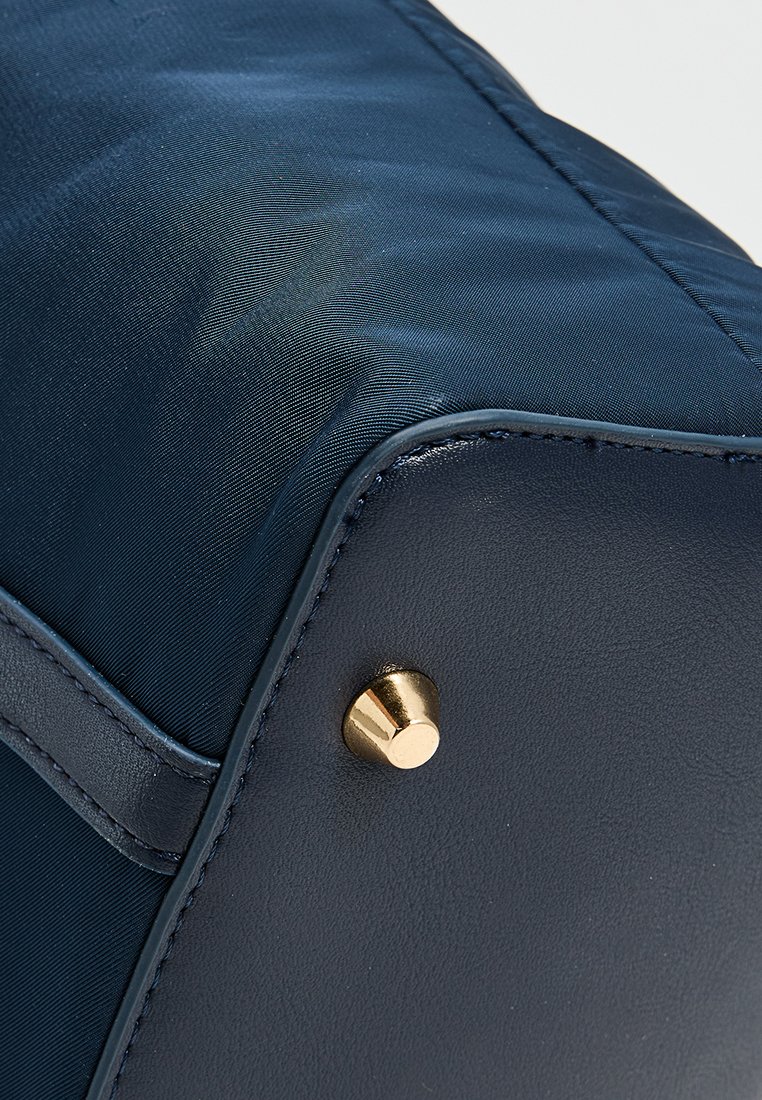 Sac bleu marin en satin et cuir, doté de quincaillerie dorée et d'une finition texturée. Bords arrondis et design épuré.