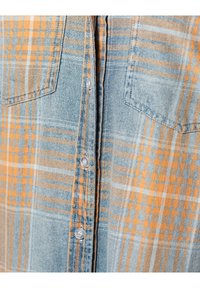 Rutig skjorta i ljusblått med orange och vita accenter. Har två bröstfickor och genomskinliga knappar. Tillverkad av bomullsdenim.