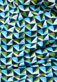 Blue, green, navy, and white geometric leaf pattern on a wrinkled fabric surface.