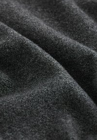 Grått, texturerat tyg med en mjuk, stickad applikation. Materialet har en subtil glans och innehåller olika nyanser av mörkgrå.