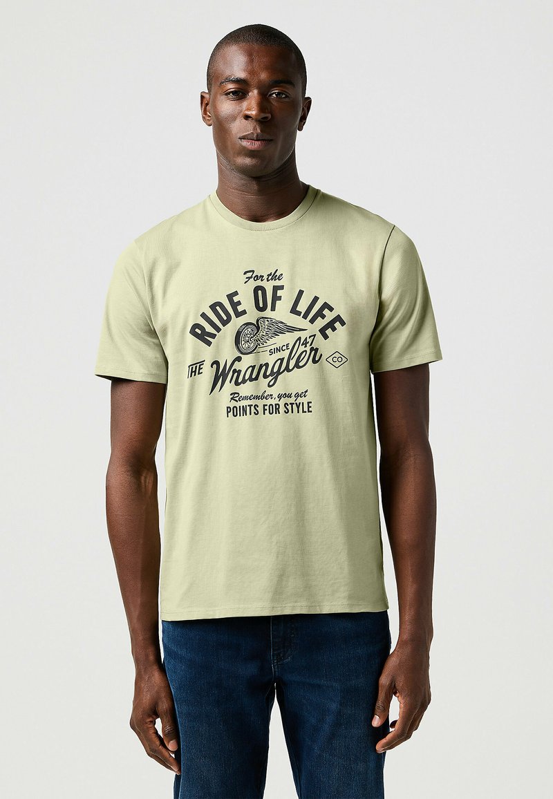 Jasnozielona bawełniana koszulka z krótkim rękawem, prezentująca czarny nadruk tekstu i grafik. Okrągły dekolt, luźny krój oraz prosty dół.