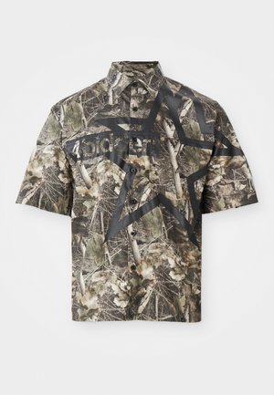 Kortærmet skjorte med knaplukning i camouflage mønster, prydet med et stort sort stjernegrafik og tekst på forsiden, samt klassisk krave og knaplukning.