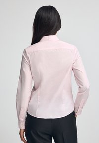 Maglietta a maniche lunghe rosa chiaro con colletto classico, design aderente e polsini con bottoni, realizzata in tessuto morbido con una trama liscia.