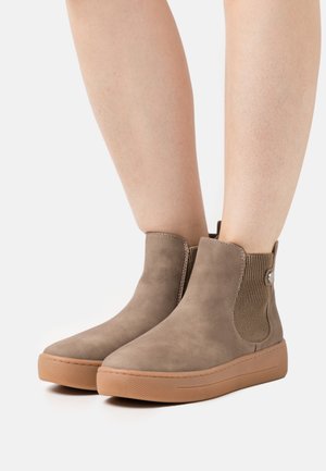 Bottes cheville en daim beige avec panneaux latéraux élastiques et semelles en caoutchouc. Bout arrondi et détails cousus. Tige texturée et design plat.