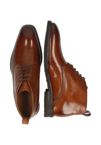 Scarpe eleganti in pelle marrone con una finitura lucida, caratterizzate da punta arrotondata, lacci e una suola in gomma bassa. Altezza alla caviglia con cuciture decorative.