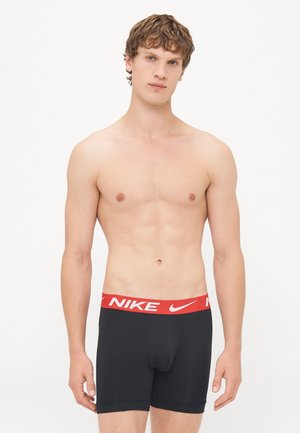 Sorte boxershorts med en rød Nike-midje, der viser logoet. Lavet af strækbart, glat stof for komfort.