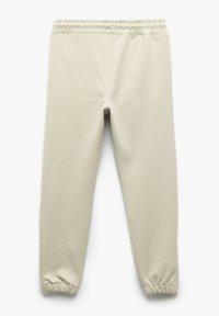 Lichtbeige trainingbroek met een gestructureerde afwerking, elastische tailleband en taps toelopende boorden. Geen zichtbare zakken of patronen.