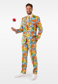 Kleurrijk pak met cartoon Pokémon-karakters in groen, oranje, blauw en geel. Inclusief bijpassende stropdas en witte sneakers.