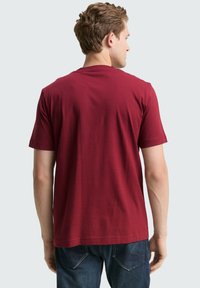 Bordeaux katoenen t-shirt met korte mouwen, ronde halslijn en een rechte zoom. De achterkant heeft een eenvoudig, onversierd ontwerp en een zachte textuur.