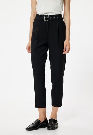 Pantaloni neri sartoriali con vita alta e una cintura larga con fibbia quadrata in argento. Tessuto morbido, lunghezza corta e pieghe frontali.