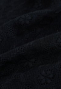 Tela de encaje negro con un patrón intrincado de diamantes y flores, con un tejido texturizado, transpirable y diseño abierto.