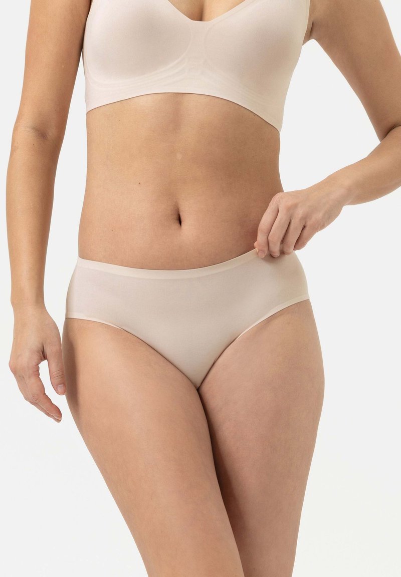 Beige naadloze slips met een medium hoge taille, gladde textuur en zachte elastische tailleband. Ontworpen voor comfort met minimale zichtbare sliplijnen.