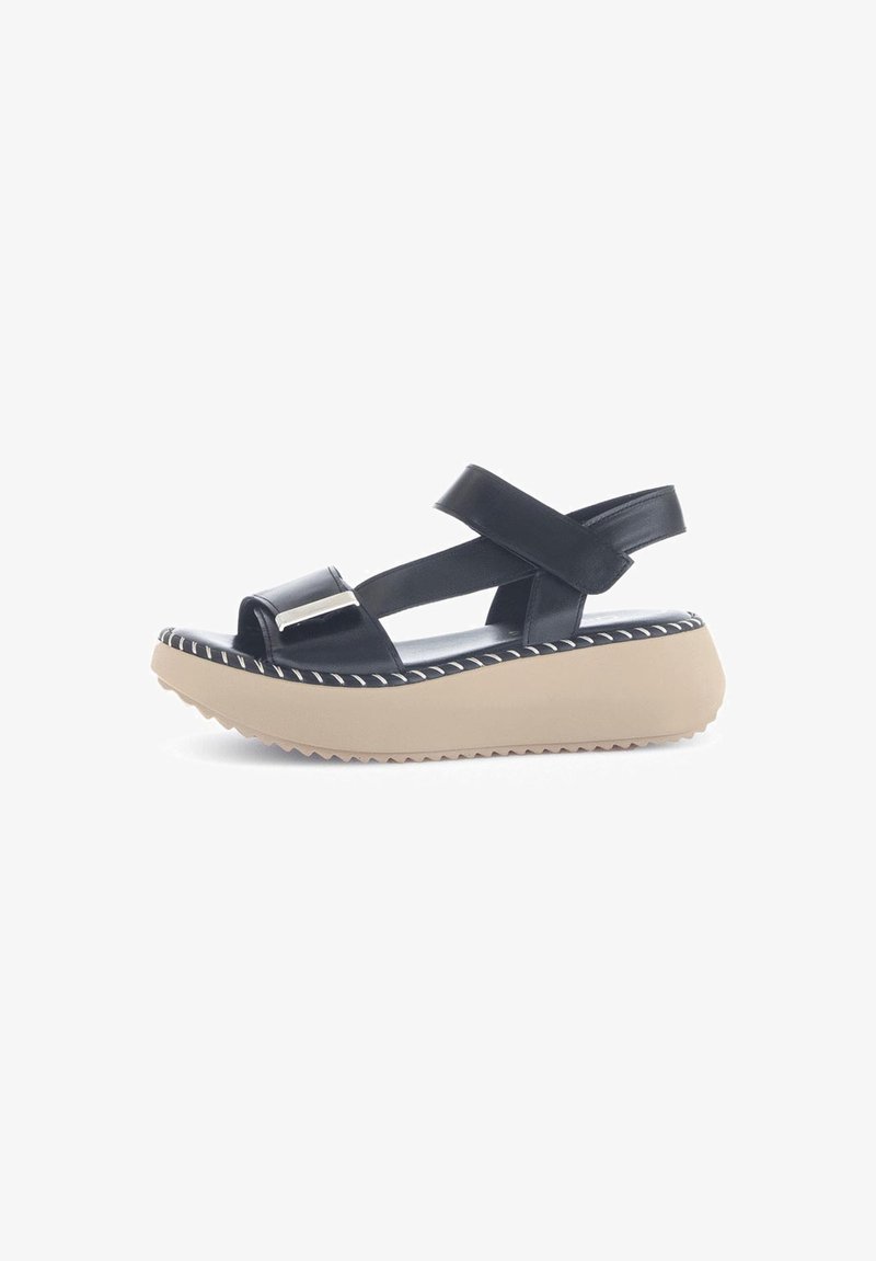 Black leather wedge sandal with crisscross straps, adjustable back, beige platform sole, and white stitching detail along the edge.