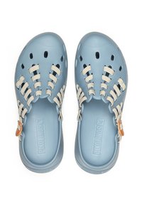 Zuecos de color azul claro con cordones elásticos de color beige, orificios de ventilación y una suela texturizada. Presentan un acento marrón cerca del talón.