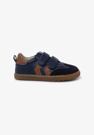 Sneaker blu navy con accenti marroni, dotata di cinturini in velcro, una parte superiore in pelle testurizzata, suola in gomma e un occhiello sul retro.