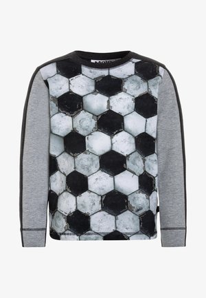 Camisa de manga larga con un patrón hexagonal que recuerda a un balón de fútbol desgastado, con mangas grises y detalles oscuros. Textura de tela suave visible.