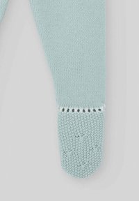 Tissu tricoté bleu clair avec un motif texturé, présentant un bout doux et arrondi avec un accent blanc en haut.