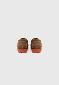 Bruna mockaskor med en orange gummisul. Har sömdetaljer och rundad form, designade för avslappnad användning.