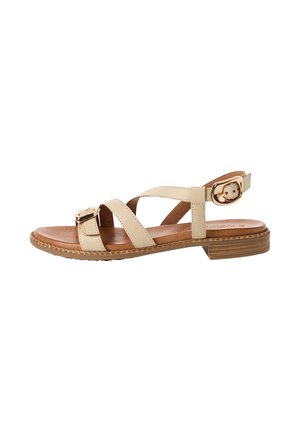 Beige flad sandal med to stropper, guldfarvede spænder, polstret brun indersål og lav stablet træhæl på hvid baggrund.