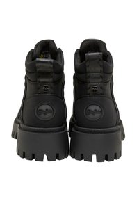 Černé vysoké boty se silnou platformou, hladkým koženým svrškem, embosovaným logem a texturovanou smyčkou na patě pro snadné obouvání.