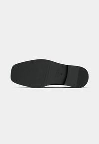 Semelle de chaussure noire présentant un design plat avec une surface texturée. Montre un logo gravé et les détails de la pointure sur la base, style minimaliste.