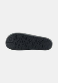 Soletta di scarpa in gomma nera con un pattern testurizzato e scanalato per la trazione, dotata di un logo circolare e linee orizzontali di accento.