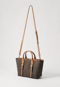 Bruine handtas met monogram en tan leren accenten, dubbele handvatten aan de bovenkant en een verstelbare schouderband; heeft een gestructureerde, rechthoekige vorm.