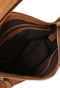 Braune Wildleder-Handtasche Innenraum, mit mehreren Taschen, einem schwarzen Stofffutter und einem Reißverschluss mit goldfarbenen Beschlägen.