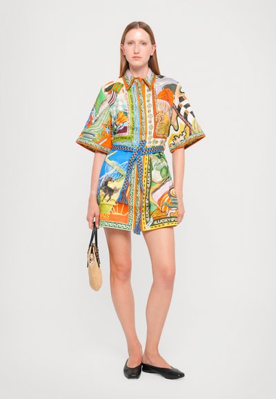 Abito corto button-up colorato con maniche larghe, caratterizzato da vari motivi e una cintura blu. Tessuto testurizzato, indossato con ballerine nere.