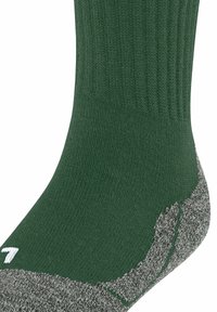 Zbliżenie zielonej skarpetki z szarym, teksturowanym spodem, z widocznym prążkowanym wzorem i białym numerem '7' z boku.