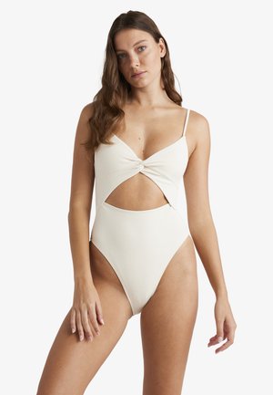 Cremefarvet ét-stykke swimsuit med et snoet frontdesign, moderat udskæring og tekstureret stof. Tynde skulderstropper og udsparinger i siden.