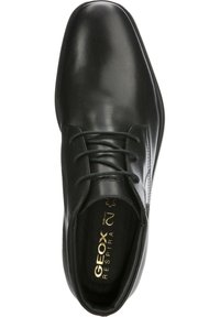 Zapato de cuero negro con un acabado suave, diseño de cordones, punta redondeada y logo dorado. Incluye plantilla acolchada para mayor comodidad.