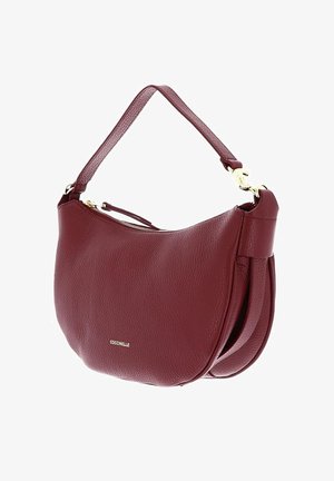 Sac d'épaule en cuir texturé bordeaux avec fermeture éclair et accessoires dorés, bandoulière unique, forme incurvée, et petit logo "Coccinelle" à l'avant.